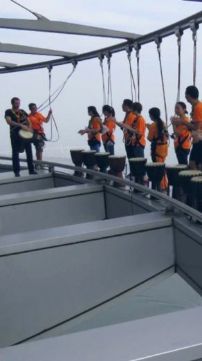 Drummers up in a tower held by harnesses