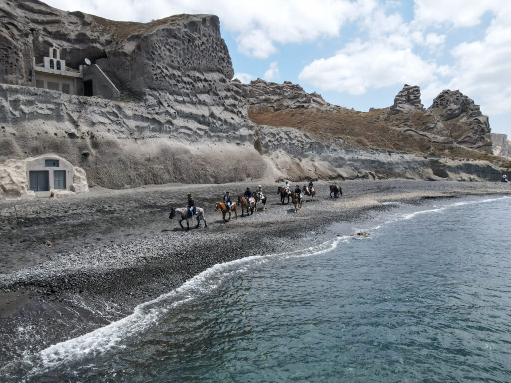 People riding horses along the water