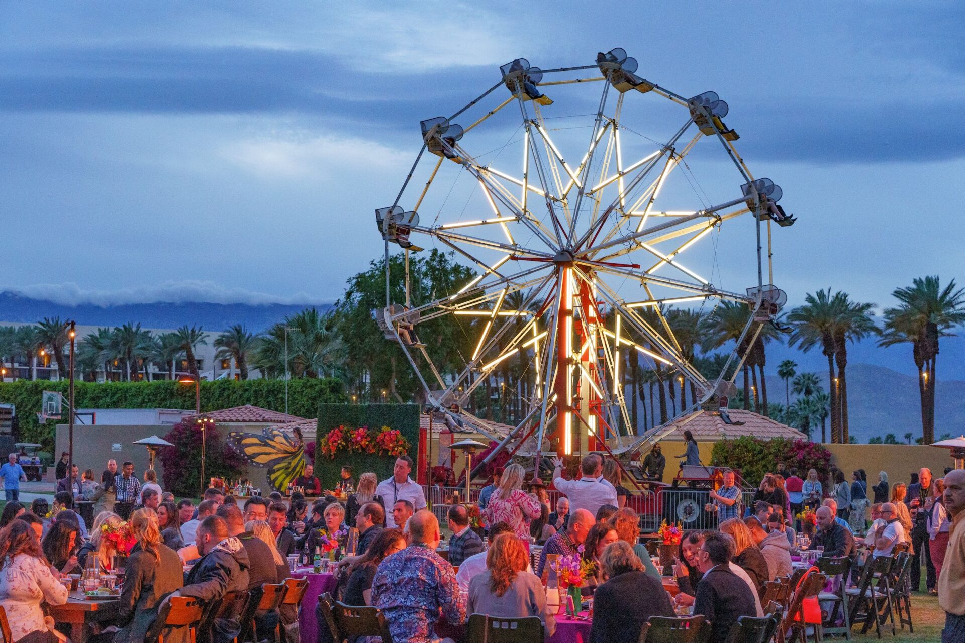 Large ferris wheel with groups of people enjoying the evening
