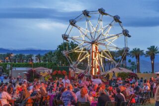 Large ferris wheel with groups of people enjoying the evening