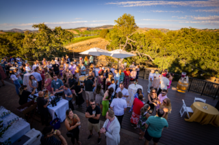 Group of people on a patio with mountains and vineyards in the background