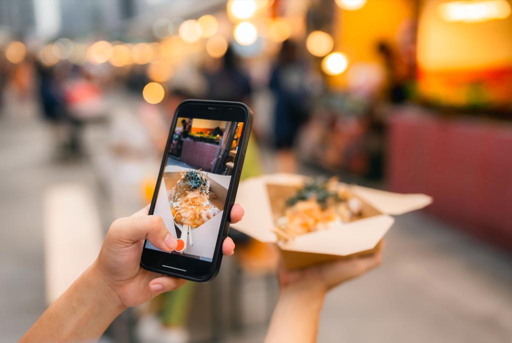 woman taking a picture of food on a smart phone phone