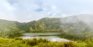 Scenic view of the crater lake inside Mount Bisoke volcano at Virunga National Park, Rwanda, surrounded by lush vegetation—popular destination for hiking and eco-tourism in East Africa.