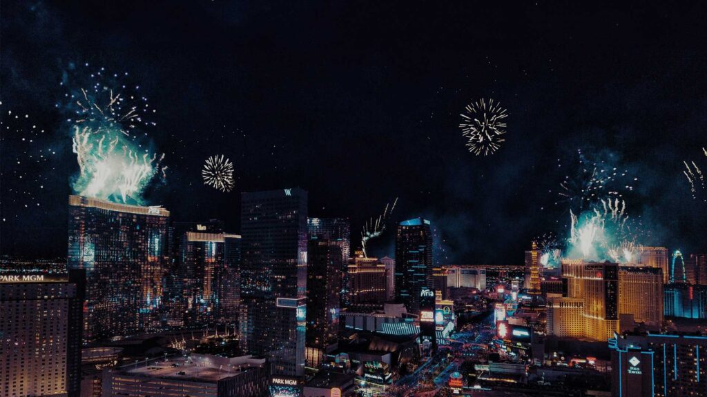 Fireworks lighting up the night sky above the Las Vegas Strip, featuring iconic hotels like Aria and Park MGM