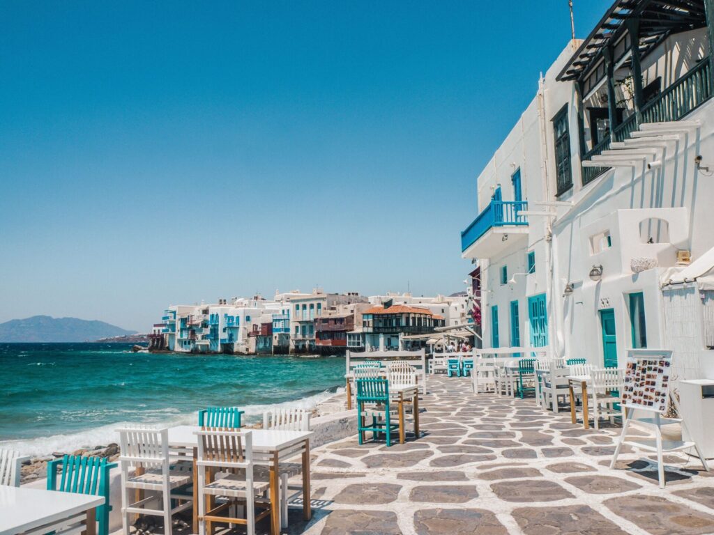 White building on the waterfront with tables scattered along the water for outdoor dining.
