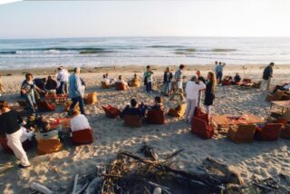 Group of people relaxing at the beach, with bonfires and comfortable sitting.