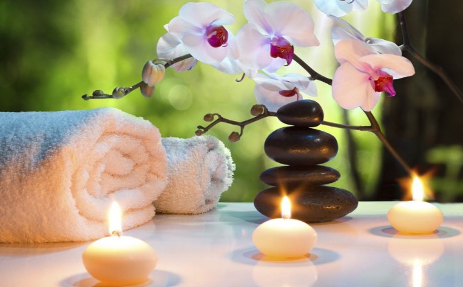 Spa table with towels, vase of orchids flowers, and tea lights