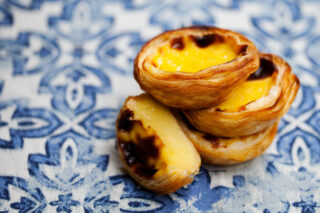 Egg tart, traditional Portuguese dessert, pastel de nata. Blue background. Close up