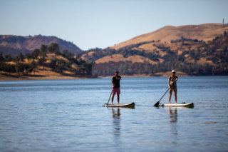 a man and a woman on stand up paddle boards on top of a lake