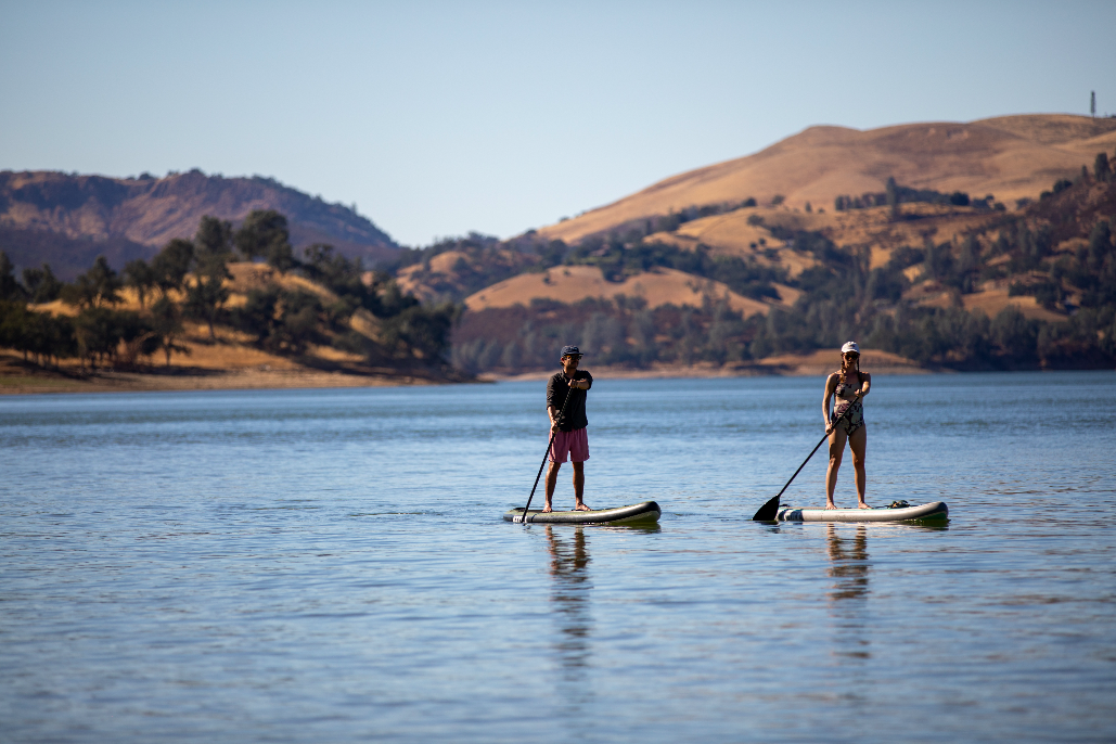 a man and a woman on stand up paddle boards on top of a lake